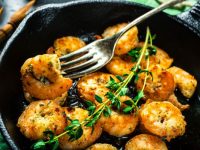 Prawns Shrimps roasted on frying cast iron pan with thyme and garlic. Party food background.